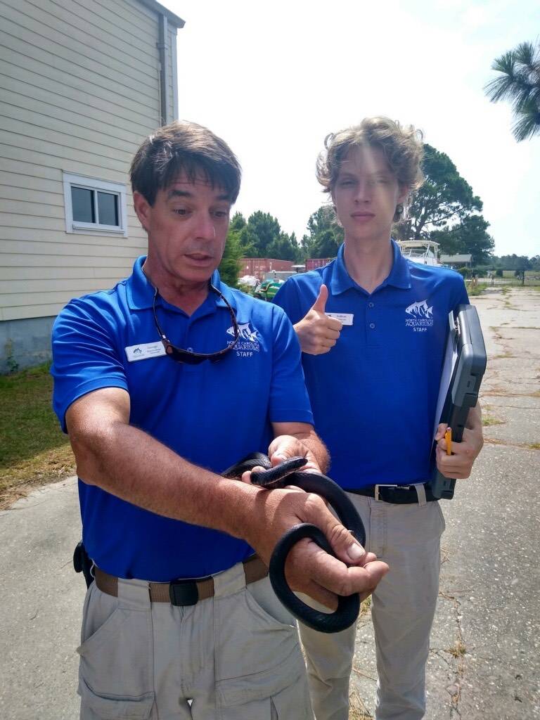 Sully standing next to an instructor holding a small snake