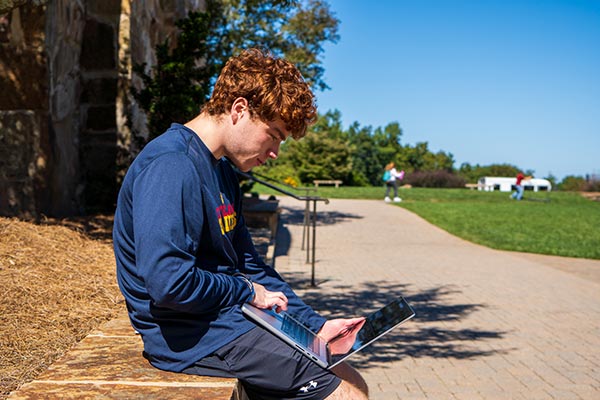 student on computer outside