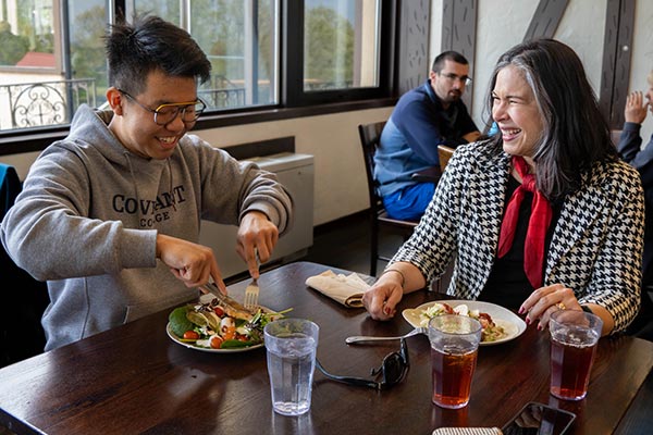 professor eating lunch with student in dining hall