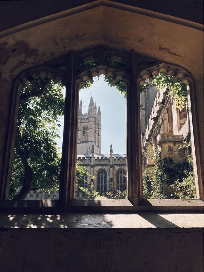 View through arches of cloisters to tower of Magdalen College , Oxford , England